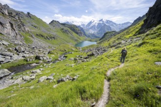 Mountaineer on hiking trail in picturesque mountain landscape, view of mountain lake Lac du Louvie
