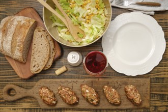 A hearty meal is prepared with freshly made meat patties, a vibrant salad with corn and greens, and