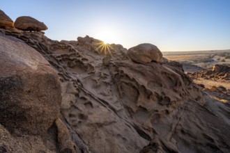 Eroded rock formations at sunrise with sun star, Erongo, Damaraland, Namibia
