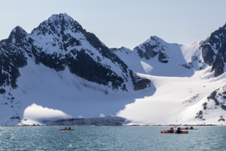 Group of canoeists Glacier and mountain range with snow, sea, Fugelfjorden, Spitsbergen, Svalbard