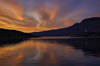 Colourful sunset over a calm lake with mountainous backdrop, Holy Week, Bay of Panormitis,