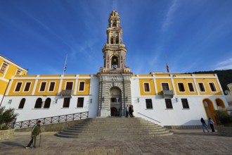 Historic building with baroque church tower and people on a square under blue sky, Holy Week,
