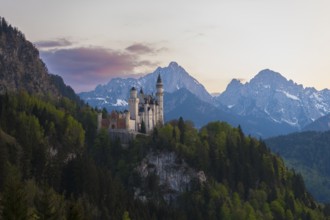 Neuschwanstein Castle against an impressive Alpine backdrop at dusk, Schwangau near Füssen,