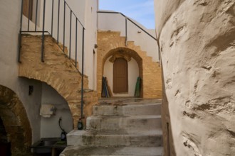 Historic courtyard with stairs, stone arches and wooden doors in the sunlight, Monastery, Moni