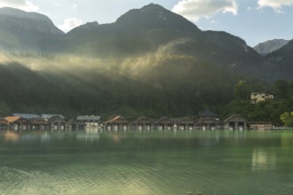 Mystical morning at Königssee in Schönau with boathouses. Sunrise and beautiful wafts of mist over