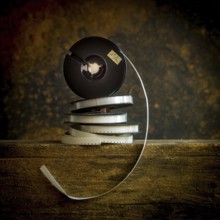 Stacked film reels rest on a worn wooden surface, highlighting the charm of vintage cinema. The