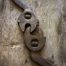 Two vintage adjustable wrenches lie closely on a rustic wooden surface, highlighting their unique