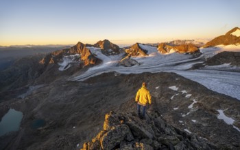 Mountaineers in front of a picturesque high mountain landscape at sunrise with alpenglow, blue