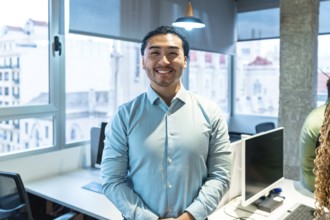 Portrait of a smiling asian businessman standing in a bright, modern office, conveying confidence