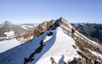 Mountaineer on rocky ridge with snow, mountain peak Wilder Freiger in the background, picturesque