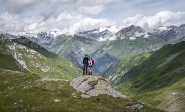 Two friends, mountaineers on a rock at the Mittagskögele, view of mountain peaks of the Venediger
