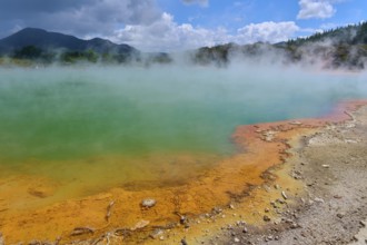 A steaming hot spring with an orange-coloured rock edge, Champagne Pool thermal lake, Wai-O-Tapu