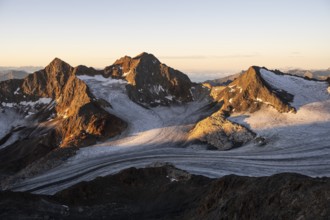 Picturesque high mountain landscape at sunrise with alpenglow, glacier and rocky mountain peaks in