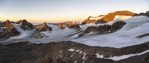 Picturesque high mountain landscape at sunrise with alpenglow, glacier and rocky mountain peaks in
