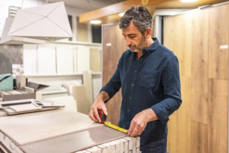 Architect choosing tile for his project, measuring large format tiles with tape measure in a home