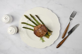 Savor a perfectly cooked filet mignon paired with tender asparagus stalks on a decorative white