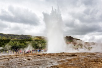 Active Strokkur, tourists observe eruption, high temperature area Haukadalur, tourist attraction at