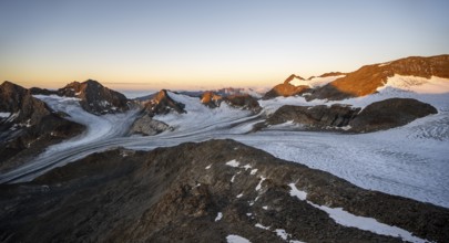 Picturesque high mountain landscape at sunrise with alpenglow, glacier and rocky mountain peaks in