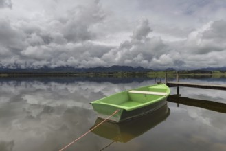 Storm clouds at sunset, a green rowing boat lashed to the wooden jetty, Hopfensee, Hopfen am See,