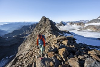 Mountaineer on a rocky ridge, ascent to the Wilder Freiger, summit of the Becher with Becherhaus