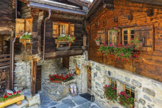 Old wooden houses in log construction, decorated with flowers, historic village centre, Grimentz,