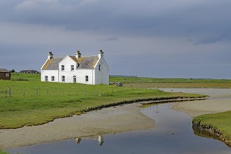 Lonely white house in a green field under a cloudy sky, Isle of Harris, Hebrides, Scotland, United
