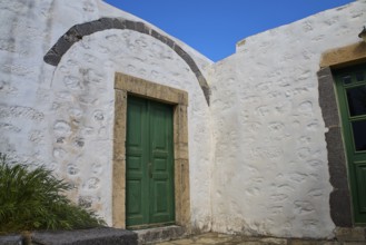 Green wooden door in a thick, whitewashed wall under a blue sky, Monastery of the Revelation, Moni