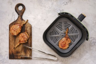 Juicy pork rib roast searing in an air fryer, alongside perfectly grilled chops resting on a wooden