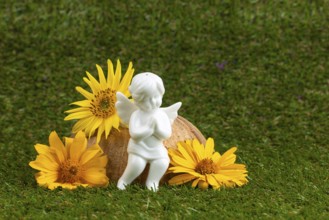 White angel figure surrounded by yellow flowers on a green lawn