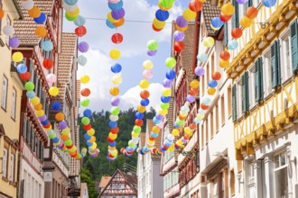 Colourful balloons decorate a narrow street in a picturesque old town under a sunny sky, Calw,