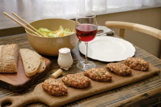 A cozy dining setup features savory meat patties served on a wooden board alongside a fresh salad