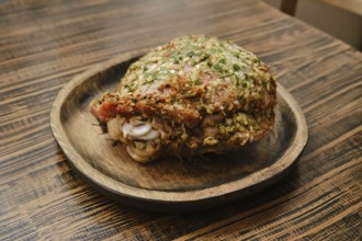 A roasted turkey thigh on a round wooden plate. The thigh is seasoned with fresh herbs, showcasing