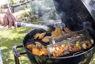 Barbecue in the garden. Meat and vegetables, vegetarian and vegan, are served on the kettle grill.
