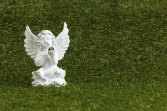 A white angel figure sits on green grass