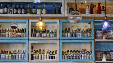 Decoratively arranged shelves with a variety of bottles and colourful elements, Taverna, Stegna