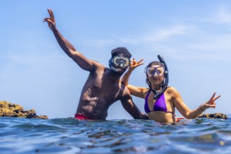 Young multi ethnic couple wearing snorkeling masks and enjoying summer vacation in tropical sea