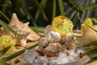 Almond and chocolate confectionery in a coconut on ice cream with umbrellas on sand