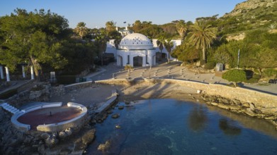 Drone shot, morning light, building with dome on a small beach with turquoise water, surrounded by
