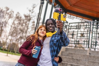Two young content creators are recording a video blog in a park, using a smartphone attached to a