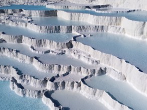 White limestone terraces with turquoise-coloured water under a clear sky, aerial view, sinter