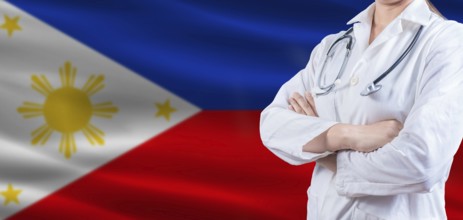Doctor with crossed arms on Philippines flag. Philippines health and care concept. Female doctor on