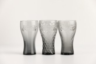 Three stylish, differently designed cola glasses in transparent and black tones
