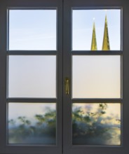 View through a closed window to the collegiate parish church of St Philip and St James, place of