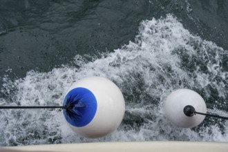 White buoys with blue markings float on moving water with whitecaps, Montenegro
