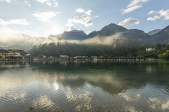 Mystical morning at Königssee in Schönau with boathouses. Sunrise and beautiful wafts of mist over