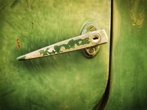 A close-up view highlights a vintage green metal latch on a door, showcasing its worn texture and