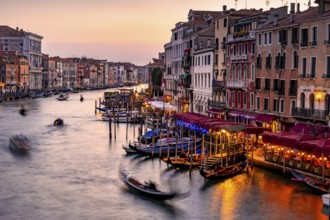 View of the Grand Canal with gondoliers at sunset, picturesque evening mood with illuminated