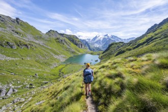 Mountaineer on hiking trail in picturesque mountain landscape, view of mountain lake Lac du Louvie