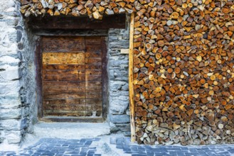 Entrance to a wine cellar framed by firewood logs, historic village centre, Grimentz, Val