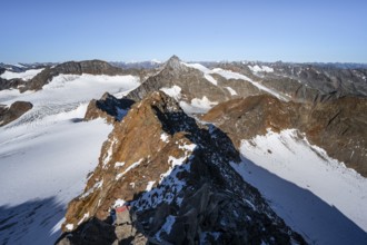 Narrow rocky ridge on the Wilder Freiger summit, picturesque high mountain landscape with snow,